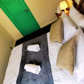 Une chambre d’hôtel avec un lit, des oreillers et une porte verte.