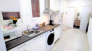 A compact kitchen with a washing machine, a sink, and a compact oven. - Beautiful furnished studio of 67 m2 (Barcelona)