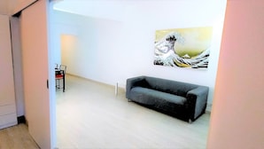 A hallway with a grey sofa, a cabinet, and a painting on the wall. - Beautiful furnished studio of 67 m2 (Barcelona)
