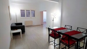 A room with a dining table, chairs, a sofa, and a radiator. - Beautiful furnished studio of 67 m2 (Barcelona)