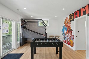 Une pièce équipée d’un baby-foot, d’un panier de basket et ornée d’une fresque représentant des personnages de dessins animés.