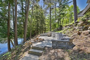 A stone staircase leading to a seating area by a body of water, surrounded by trees.