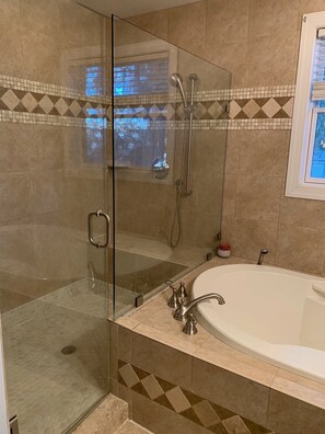Ein modernes Badezimmer mit einer gläsernen Duschkabine, einer freistehenden Badewanne und einem Fliesenboden mit geometrischem Muster.