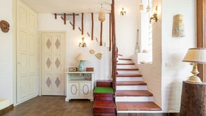 A staircase with wooden steps and a green mat, a white door with diamond patterns, a cabinet with a radio, and wall-mounted lights. - Villa 'Nuràya' with Sea View and Private Terrace (Capoterra)