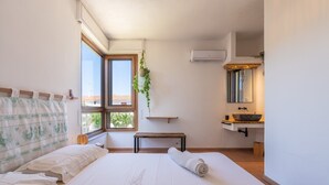 A bedroom with a large bed, a window, a bedside table, a hanging plant, a bench, a sink, and a mirror. - Villa 'Nuràya' with Sea View and Private Terrace (Capoterra)