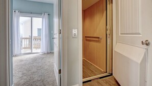 Une porte ouverte donnant sur une pièce au plancher de bois et offrant une vue sur un balcon.