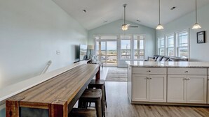 Une cuisine moderne avec une table à manger en bois, des meubles blancs et un grand îlot central.