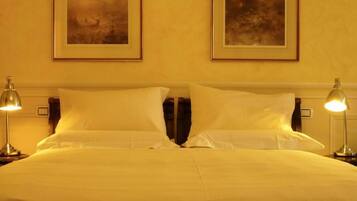 Quarto de hotel com uma cama grande, duas luminárias de cabeceira e duas molduras na parede.