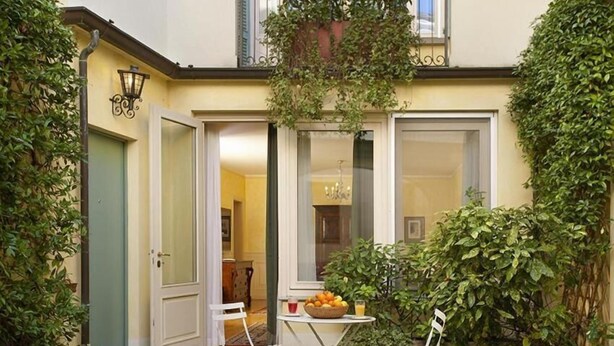 A small courtyard with a table and chairs, a door, and a window. - Relais Vimercati (Crema)