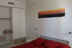 A bedroom with a bed, a nightstand, a wardrobe, and a painting on the wall.