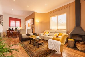 A living room with a sofa, armchairs, a coffee table, a fireplace, and a dining area with a table and chairs.