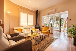 A modern living room with a sofa, armchairs, a coffee table, and a fireplace.