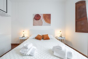 A neatly made bed with white linens, two bedside tables with lamps, and a painting on the wall. - Holiday Home 'Raggio Di Luna 2' with Private Terrace, Wi-Fi and Air Conditioning (Villasimius)