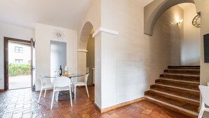 Ein modernes Interieur mit Fischgrätparkett, einer Treppe und einem Essbereich mit weißen Stühlen und einem Glastisch.