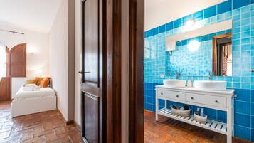 Un bagno con piastrelle blu, un mobile lavabo bianco e un letto con testiera in legno.