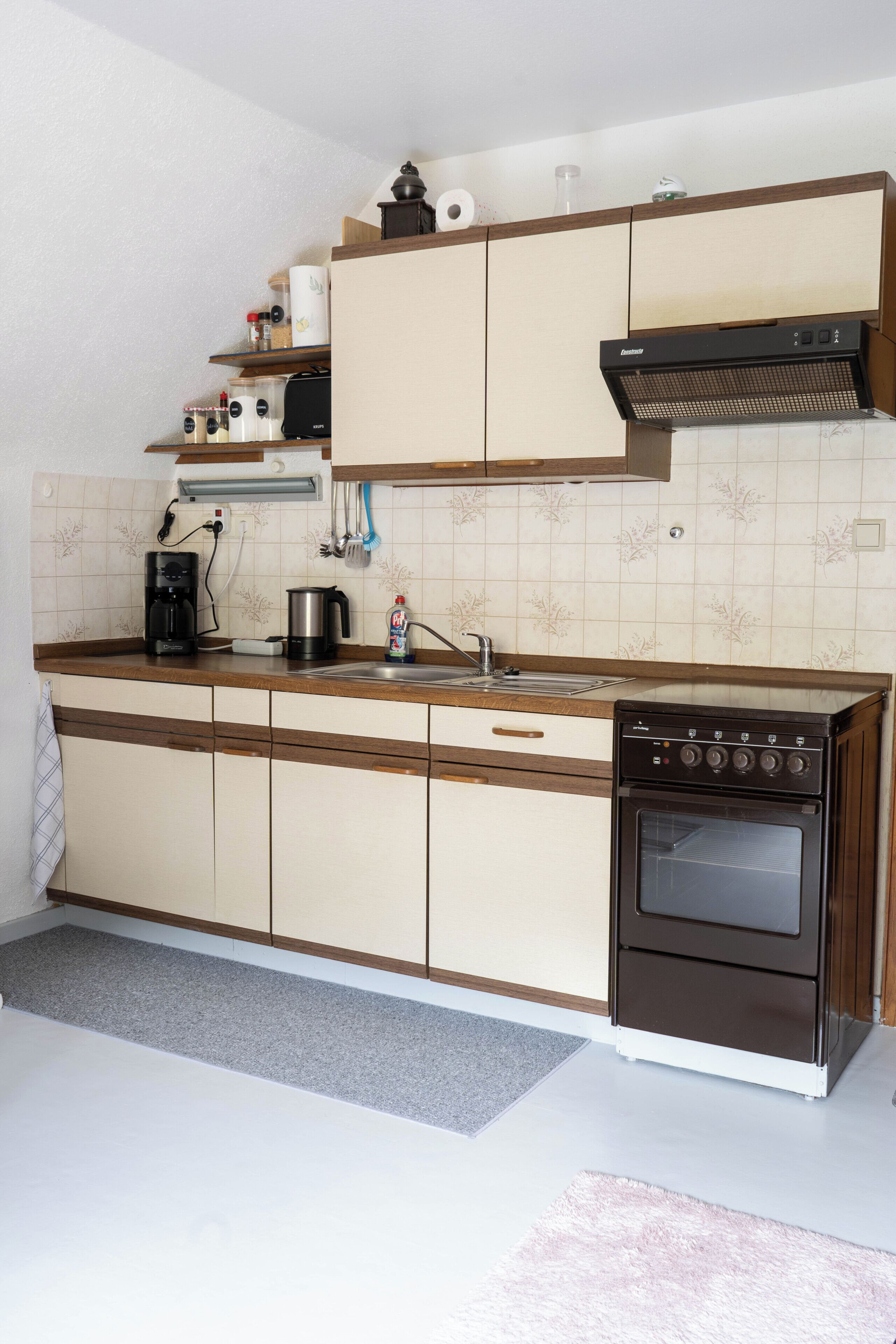 Eine Küche mit Herd, Kaffeemaschine und verschiedenen Küchenutensilien.