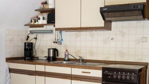 Una cocina con estufa, cafetera y diferentes utensilios.