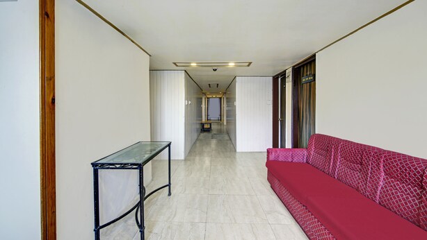 A hallway with a red patterned sofa, a small table, and a door leading to another room. - Itsy Hotels Crystal Palace Shimla With Valley View (Shimla)