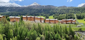 A row of wooden cabins with a mountain backdrop. - 'Chalet Pramaria - Apt L'Arcelle' with Mountain View, Wi-Fi and Air Conditioning (Lanslebourg Mont Cenis)