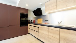 A modern kitchen with built-in appliances, wooden cabinets, and a black countertop. - Apartment 'Chalet La Turra' with Mountain View, Wi-Fi and Air Conditioning (Lanslebourg Mont Cenis)