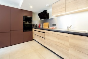Eine moderne Küche mit eingebauten Geräten, Holzschränken und einer schwarzen Arbeitsplatte.