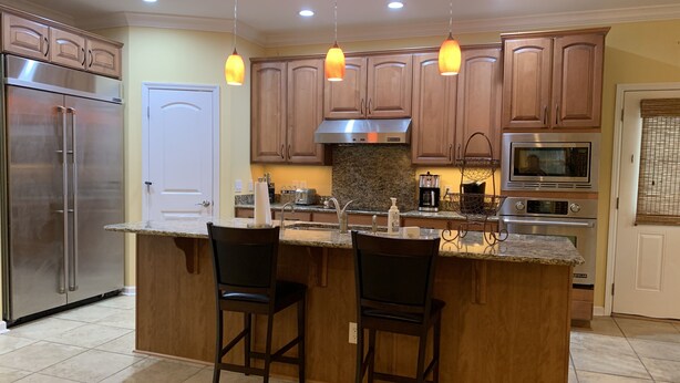 A kitchen with wooden cabinets, a stainless steel refrigerator, a microwave, and a granite countertop.