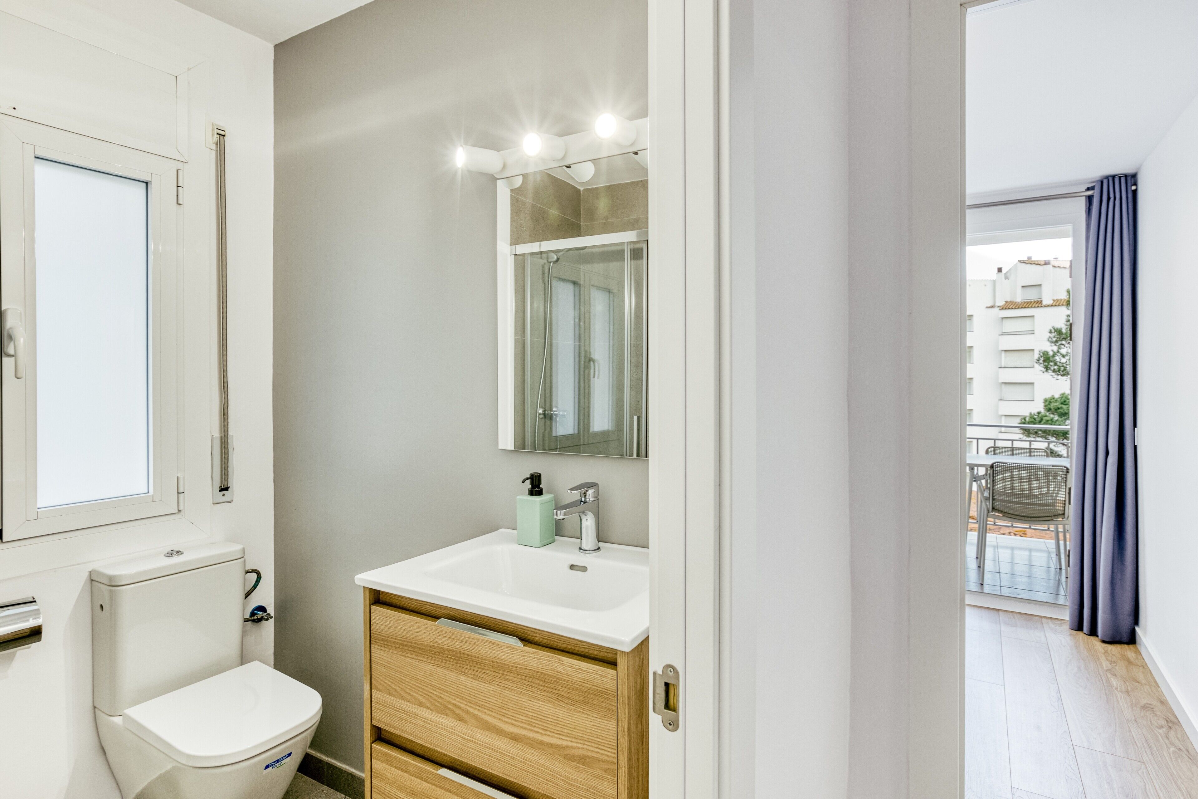 A bathroom with a toilet, sink, and mirror.