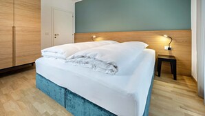 A neatly made bed with white linens, a wooden headboard, and a bedside table with a lamp. - Apartment "Avia Living" with Mountain View, Balconies & Wi-Fi (Brunico)