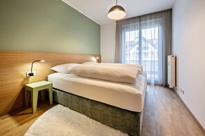 A bedroom with a bed, bedside table, lamp, and a window with curtains.