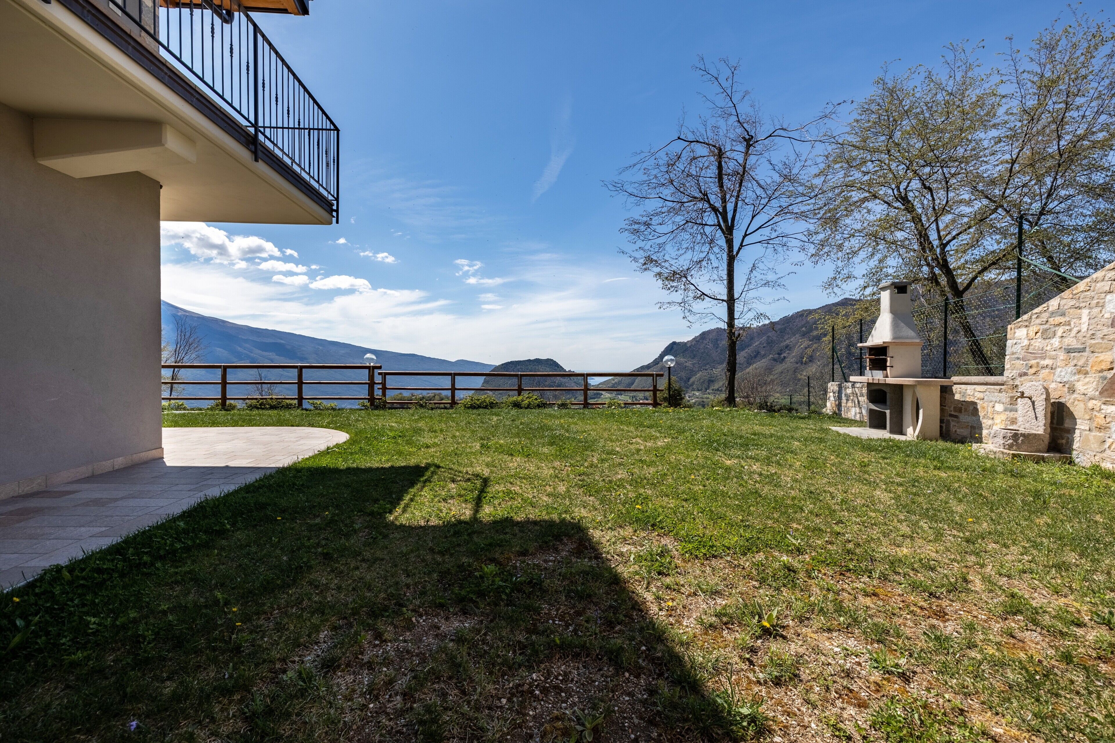 Ein Haus mit Balkon, Steinofen und Blick auf Berge und einen See.