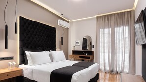 Un dormitorio moderno con una cama grande, mesitas de noche, un escritorio y un televisor.