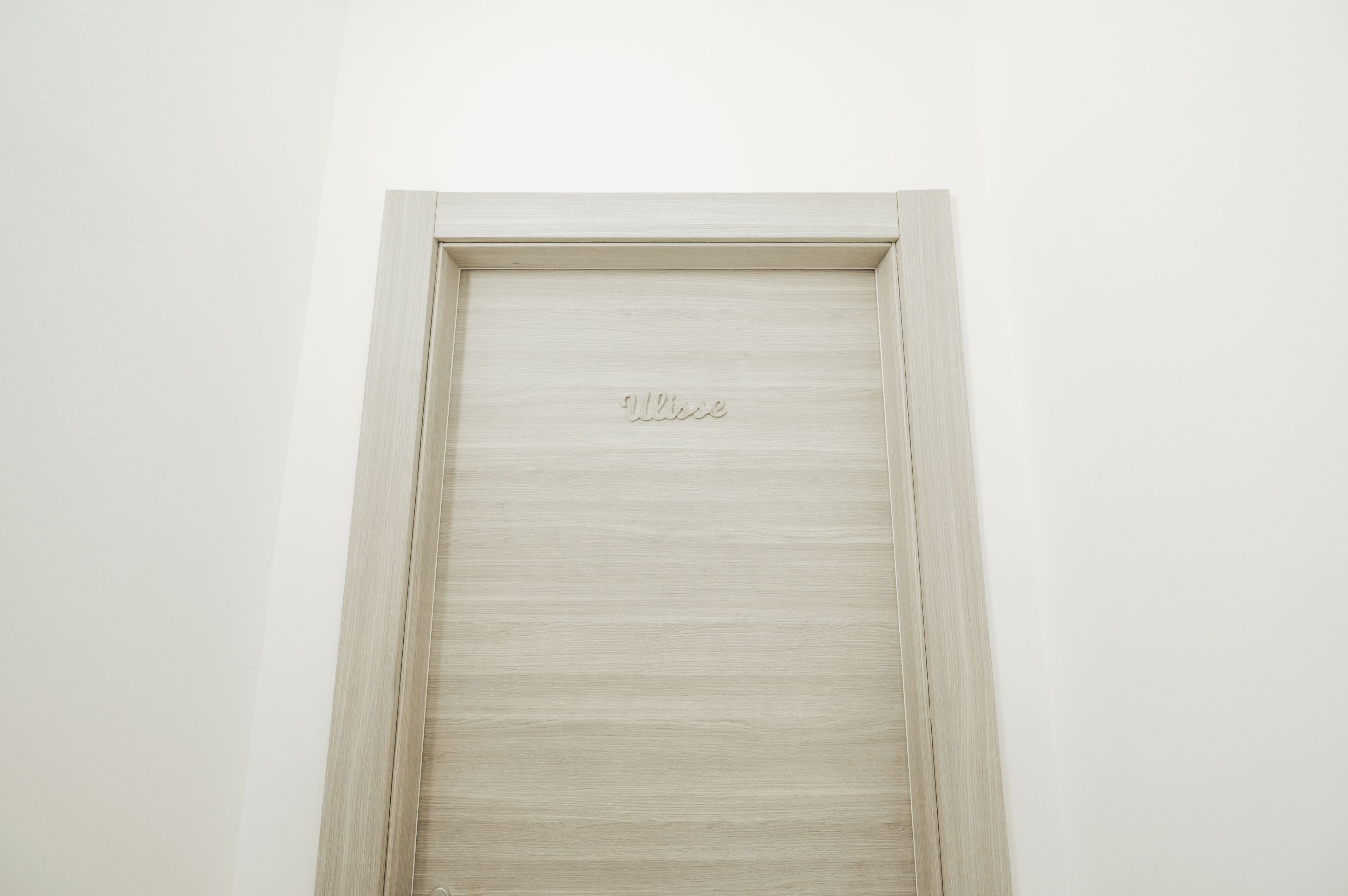 Una puerta sencilla de color claro con la palabra "Ultime" grabada.
