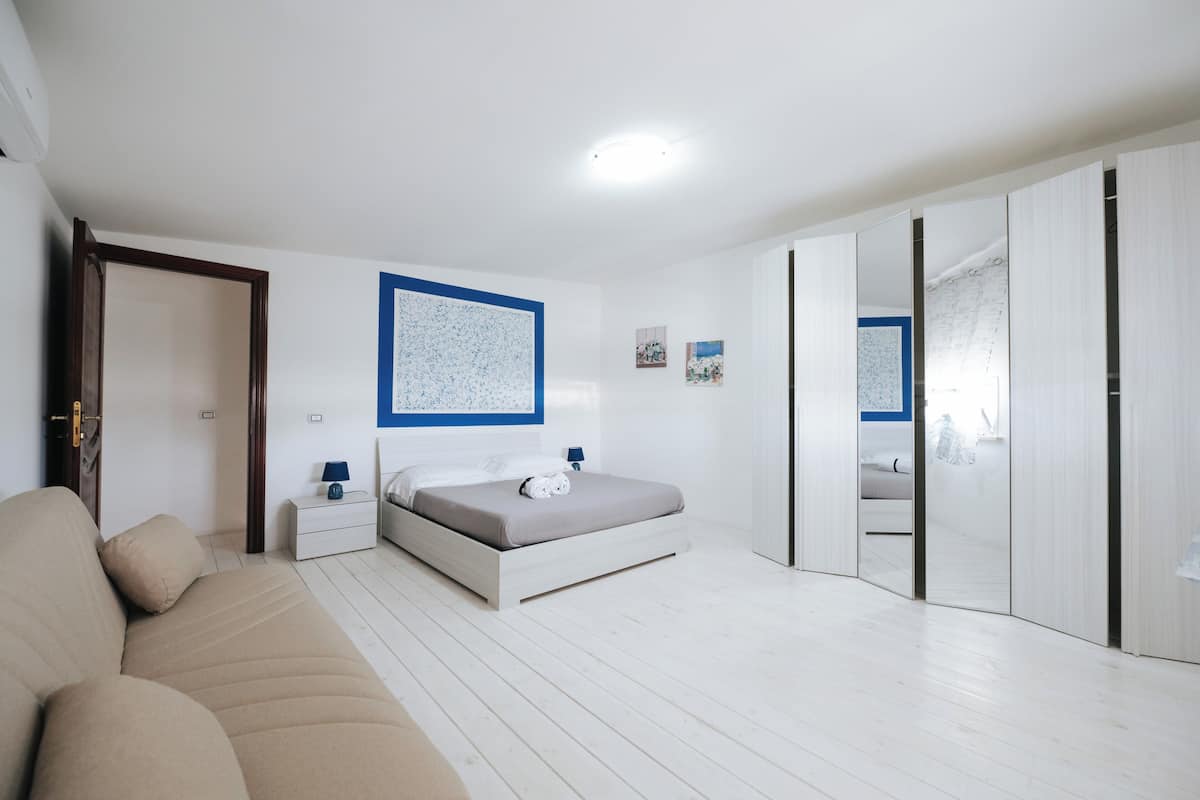 Quarto com cama, mesas de cabeceira, guarda-roupa e espelho.