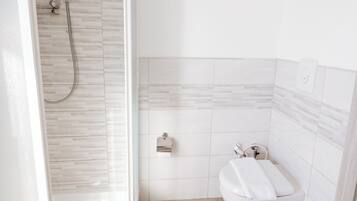 Ein Badezimmer mit einer Duschkabine, einer Toilette und einem Waschbecken.