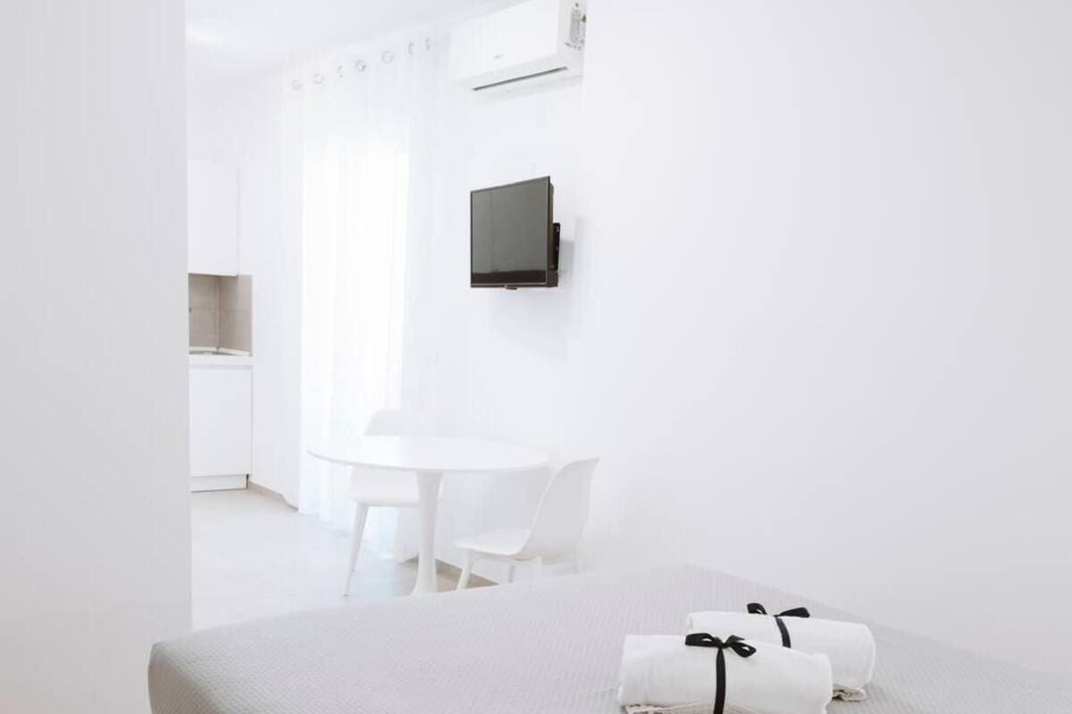Quarto de hotel moderno com uma cama, uma escrivaninha e uma TV fixada na parede.