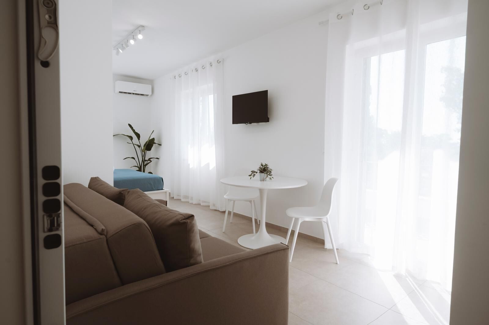 Una sala moderna con un sofá, una mesita y un televisor montado en la pared.