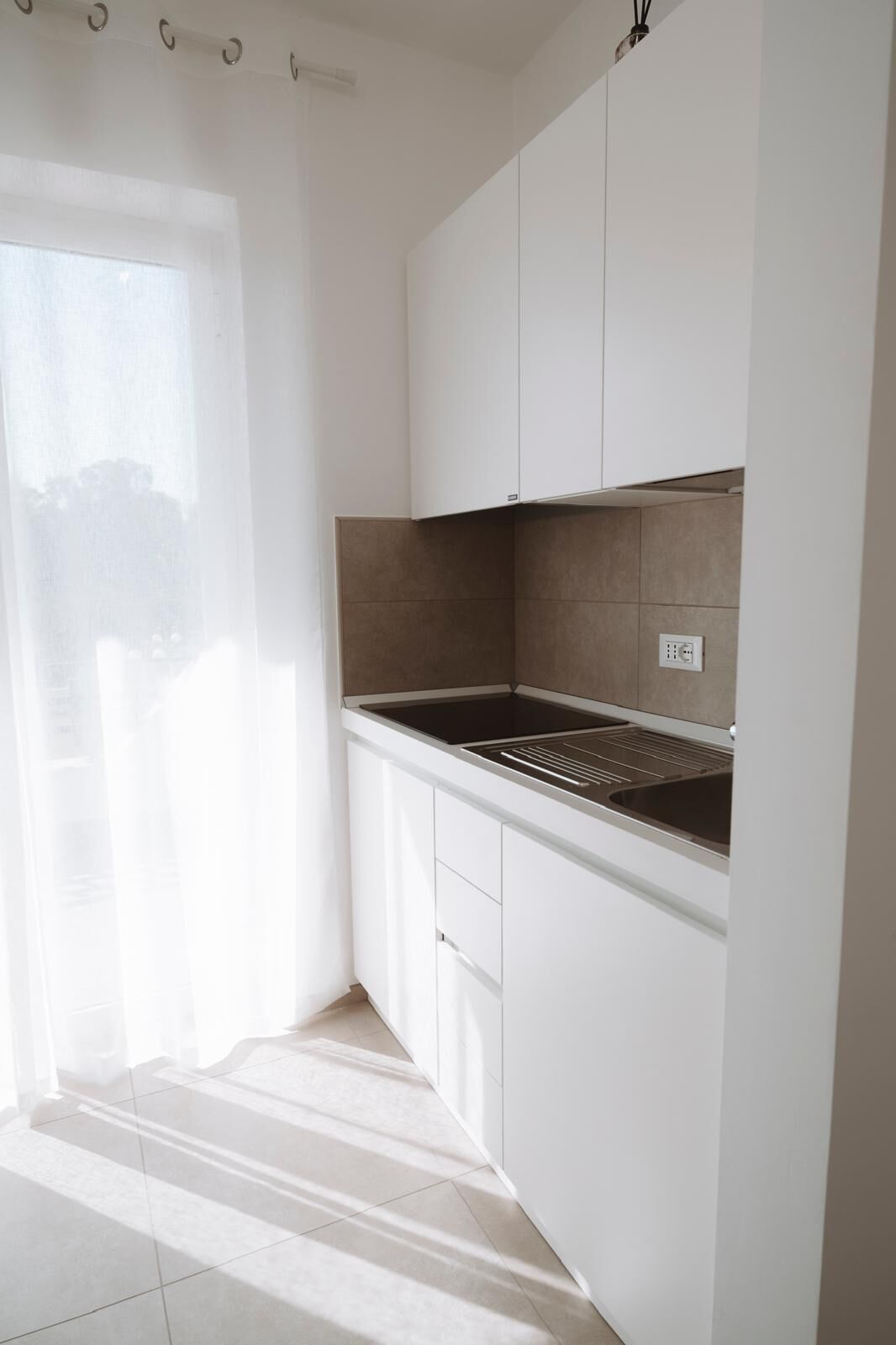 A kitchen with white cabinets, a black countertop, and a tiled backsplash.