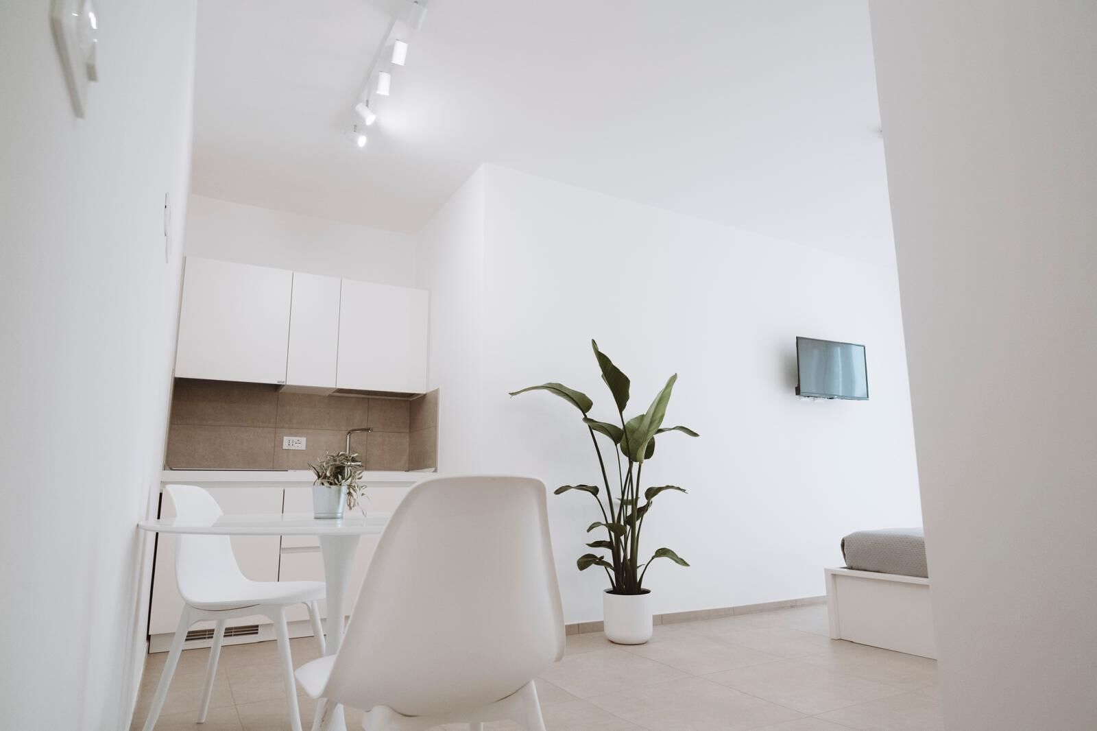 Uma sala de estar moderna e minimalista com área de jantar, cozinha e televisão de tela plana na parede.