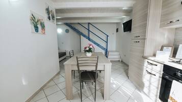 Una cocina moderna con comedor, una escalera y un televisor de pantalla plana en la pared.