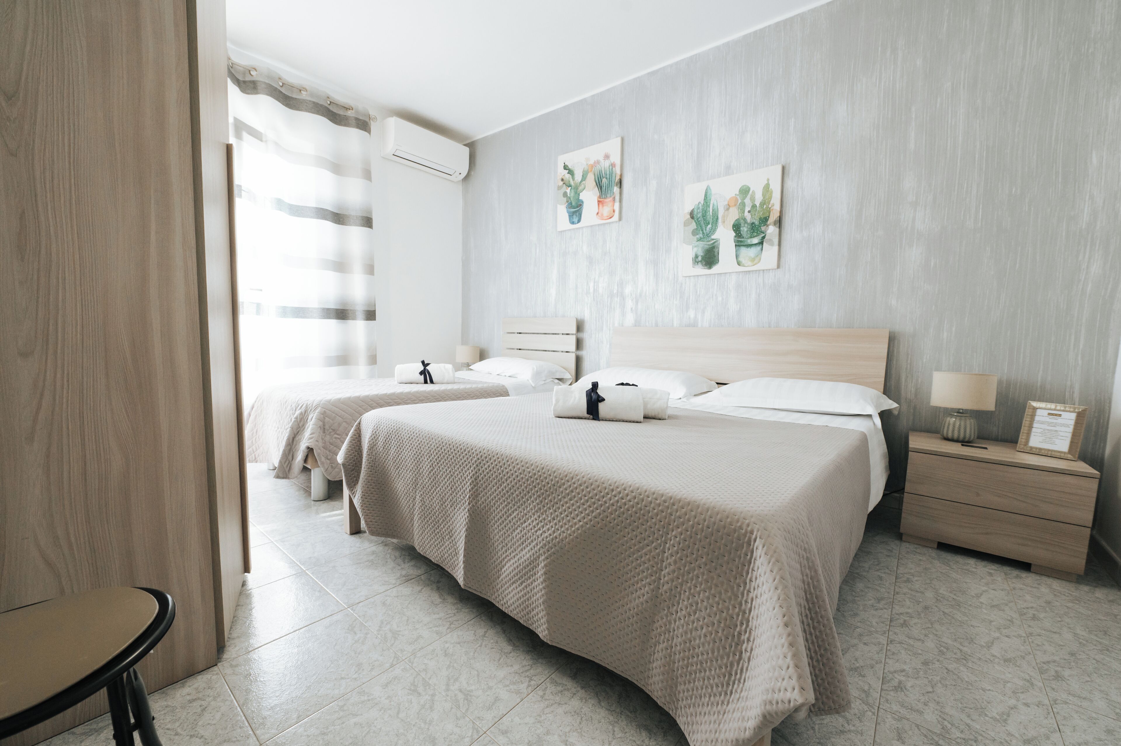 Habitación de hotel con dos camas, una mesita de noche con lámpara y una obra de arte en la pared.