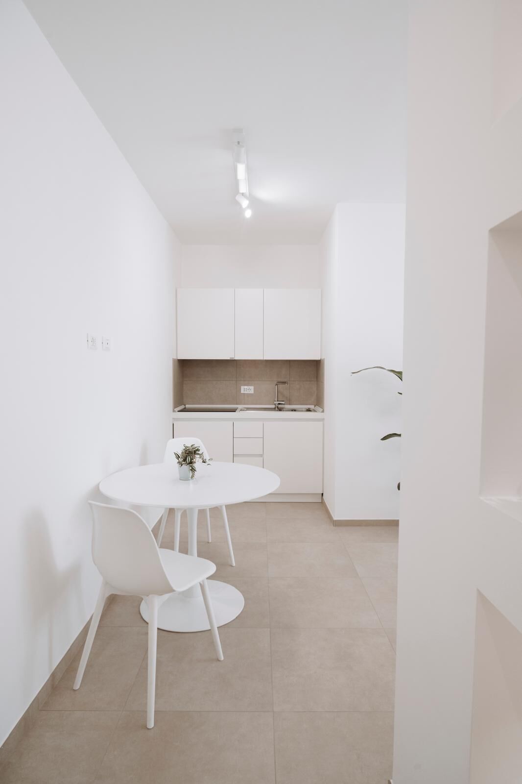 Une cuisine moderne et épurée, avec des meubles blancs et un îlot central.