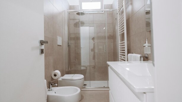 A modern bathroom with a glass shower enclosure, a toilet, a bidet, and a sink. - GIOEMA (Sabaudia)