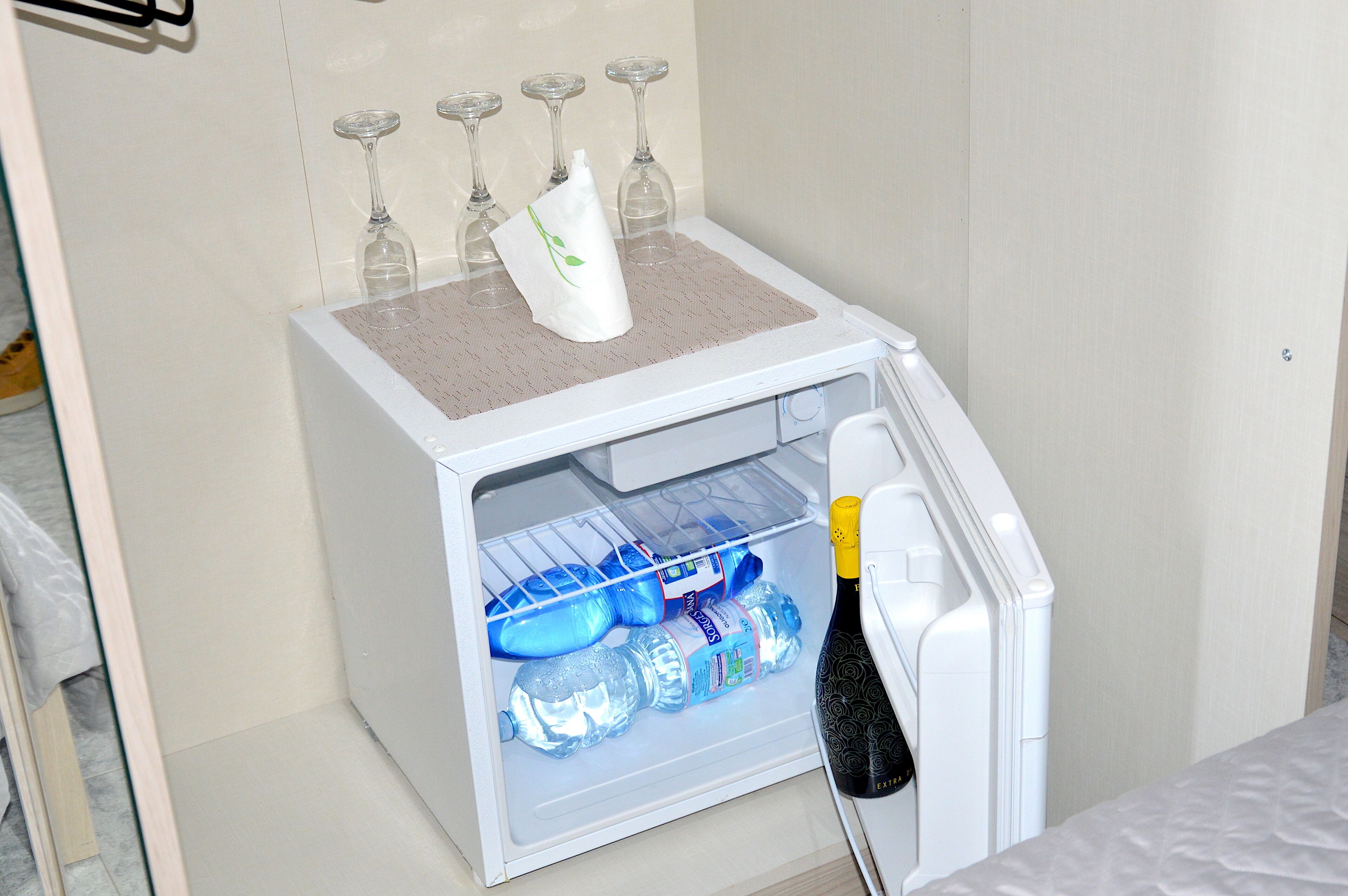 Een minibar met een champagnefles, verschillende waterflessen en wijnglazen.