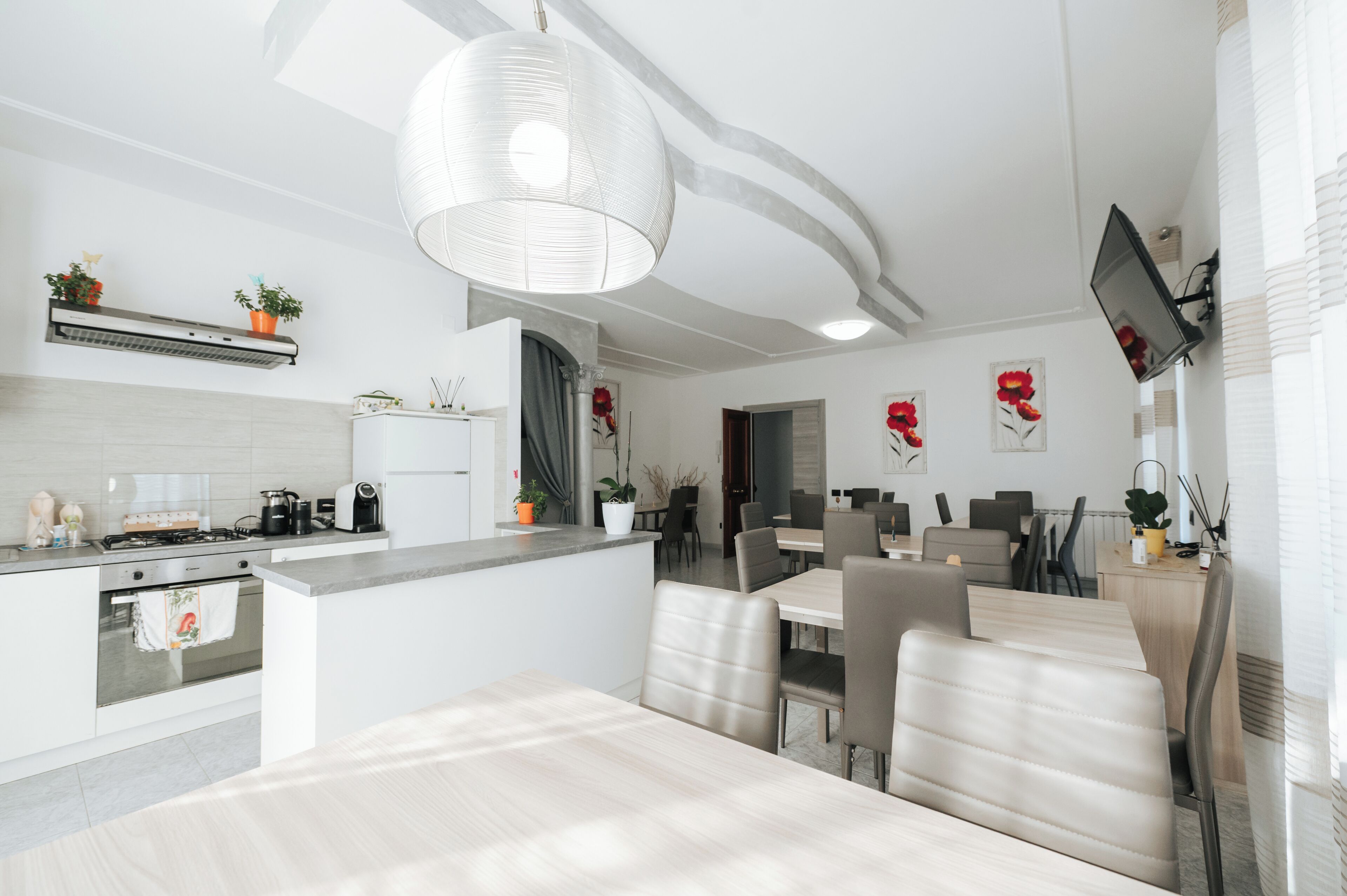 A modern kitchen with a dining area, featuring a central island, built-in appliances, and a large pendant light.