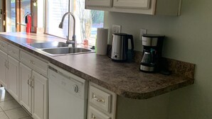 A kitchen with white cabinets, a stainless steel sink, a coffee maker, and a dishwasher. - Quality comfort in a convenient location (entire house) (Beaufort)