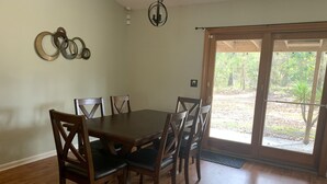 A dining area with a wooden table and chairs, a chandelier, and a sliding glass door leading to an outdoor area. - Quality comfort in a convenient location (entire house) (Beaufort)