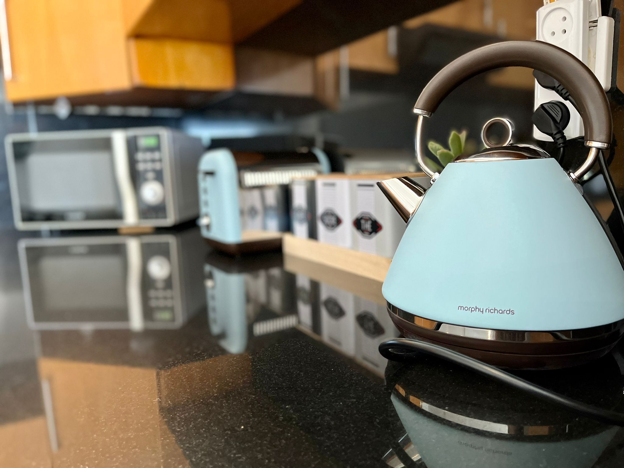 A kitchen with a kettle, microwave, and toaster on the counter.