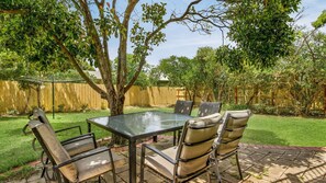 A patio with a glass table and six chairs, surrounded by a wooden fence and trees. - Woolamai Sands in Cape Woolamai (Cape Woolamai)