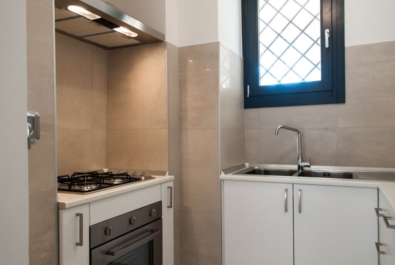 Una cocina compacta con estufa a gas, horno y pileta con grifo moderno.