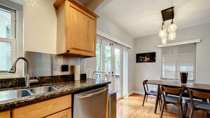 Eine Küche mit Granit-Arbeitsplatten, Holzschränken, Edelstahlgeräten und einem Essbereich mit Tisch und Stühlen.